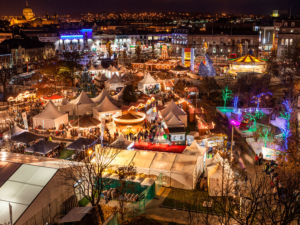 Vibrant evening market with festive lights, colourful stalls, and a lively atmosphere in the city centre near the hotel.
