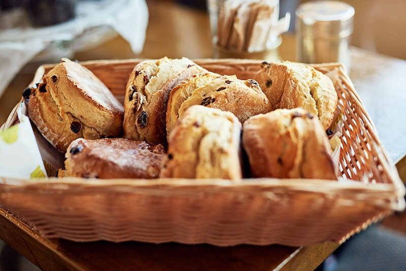Freshly baked scones in a wicker basket, inviting guests to enjoy a delightful afternoon tea at our cosy hotel café.