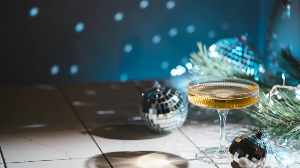 A glass with a drink and disco balls.