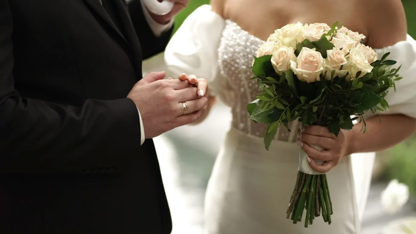 Couple exchange rings in elegant wedding ceremony with lush bouquet, creating romantic memories at luxurious hotel venue.