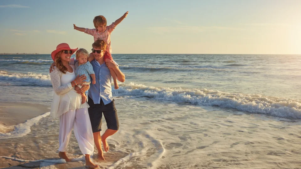 Family enjoying a sunny day on a sandy beach with gentle waves, perfect for a delightful seaside holiday experience.