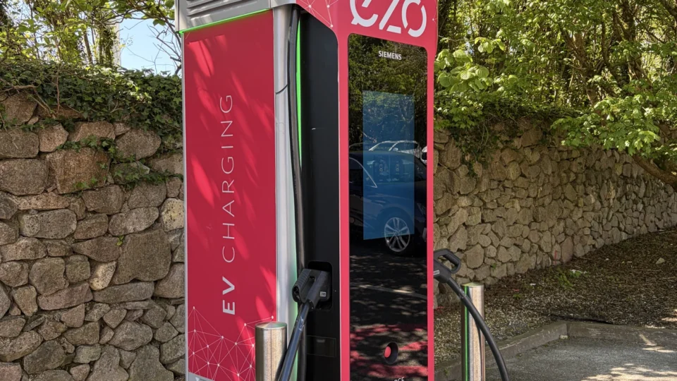 Eco-friendly electric vehicle charging station at hotel car park under lush trees, providing 100% renewable energy.