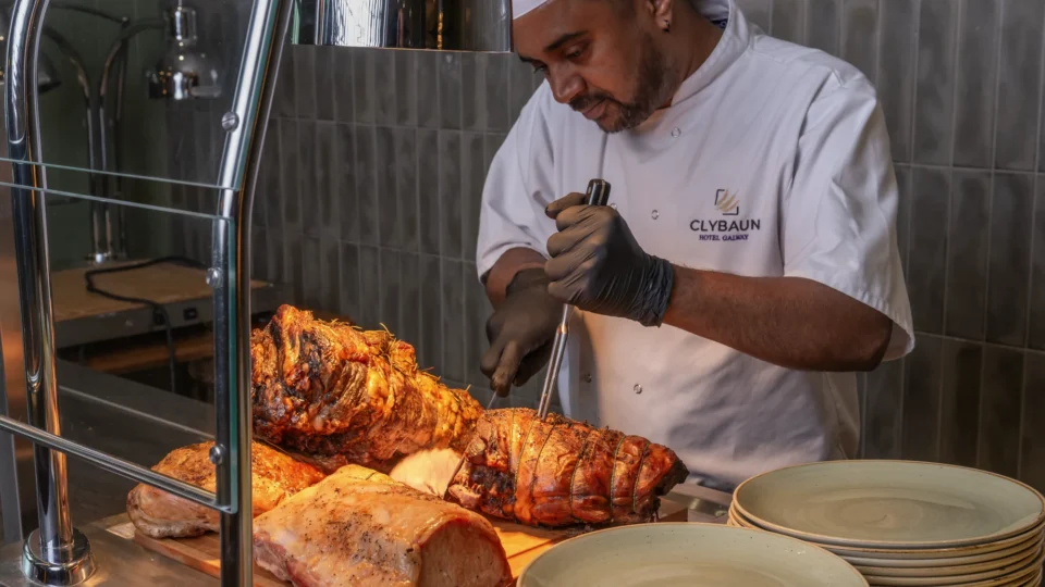 Chef carving roast meats at Clybaun Hotel buffet, showcasing delicious dining options; warm, inviting gourmet experience.
