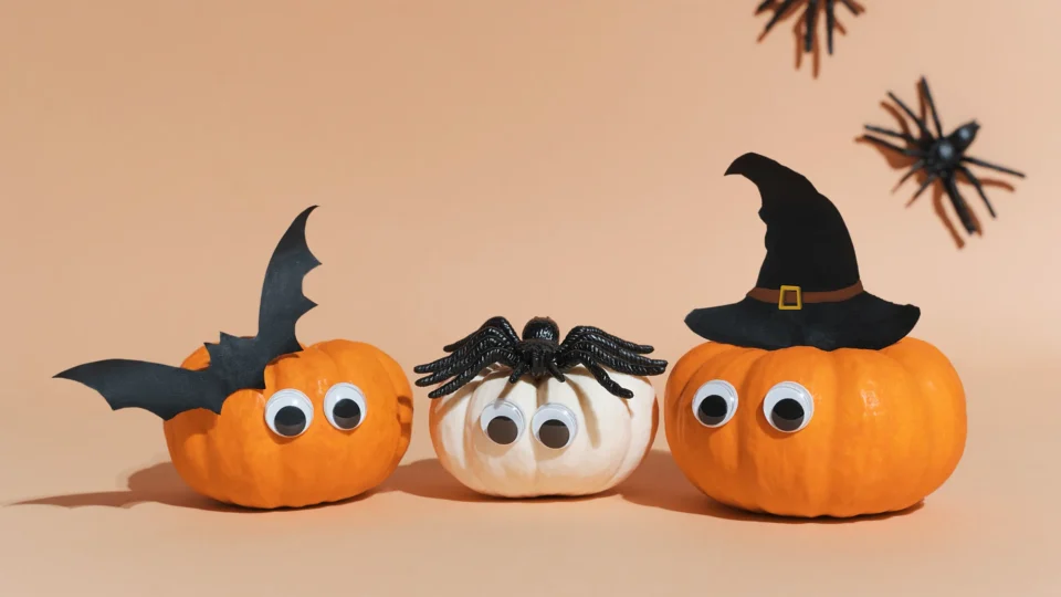 Playful Halloween pumpkins with googly eyes, decorated as a bat, spider, and witch, creating a festive atmosphere.