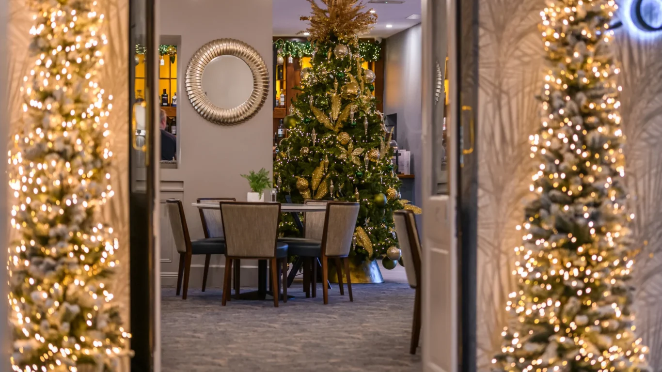 Cosy hotel dining with festive Christmas tree and elegant decor, offering a warm and inviting atmosphere for guests.
