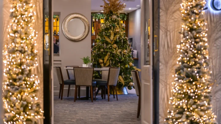 Cosy hotel dining with festive Christmas tree and elegant decor, offering a warm and inviting atmosphere for guests.