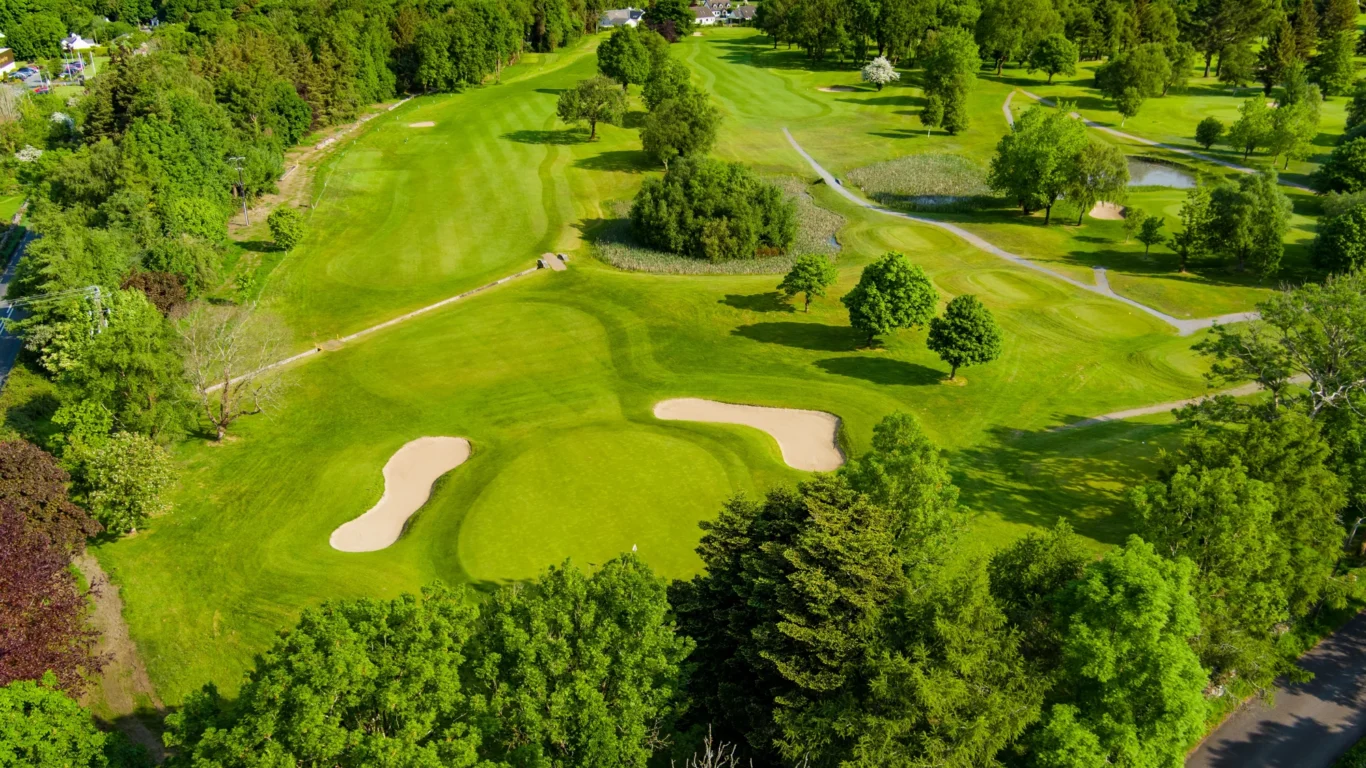 Expansive hotel golf course with lush fairways, mature trees, and scenic water views for a relaxing getaway.