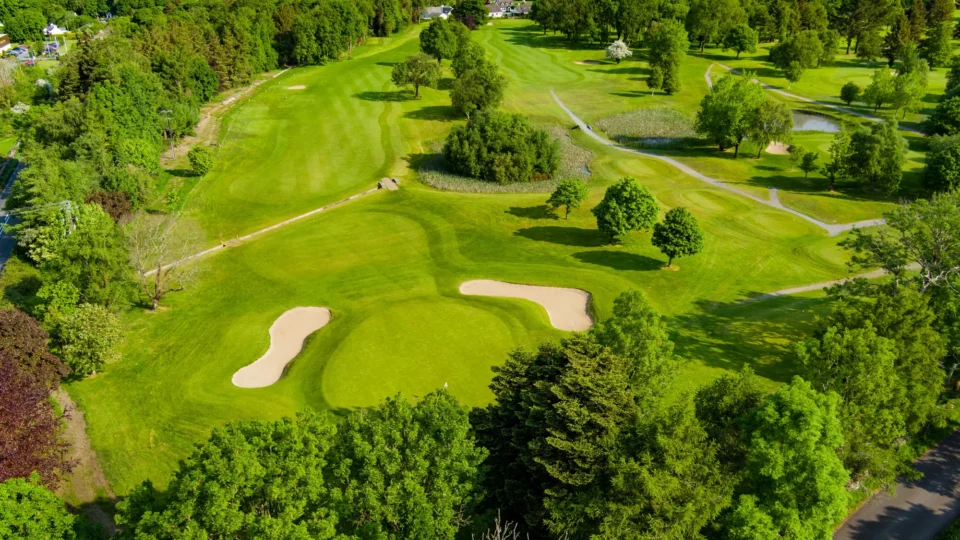 Expansive hotel golf course with lush fairways, mature trees, and scenic water views for a relaxing getaway.