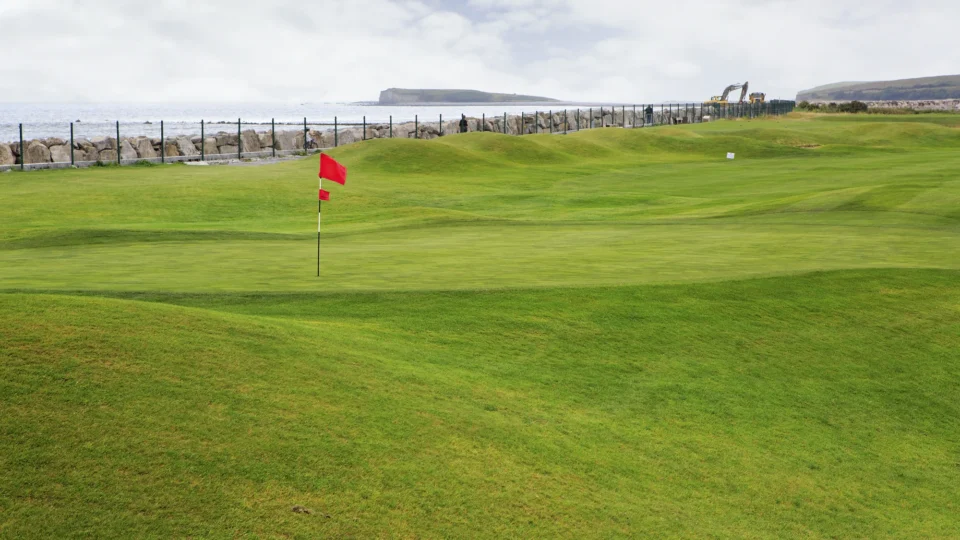 Coastal golf course with lush green fairways and stunning sea view, perfect for a relaxing stay and golfing experience.